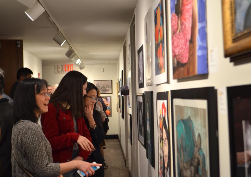 Visitors look at a hallway full of students gold-key-winning artworks.